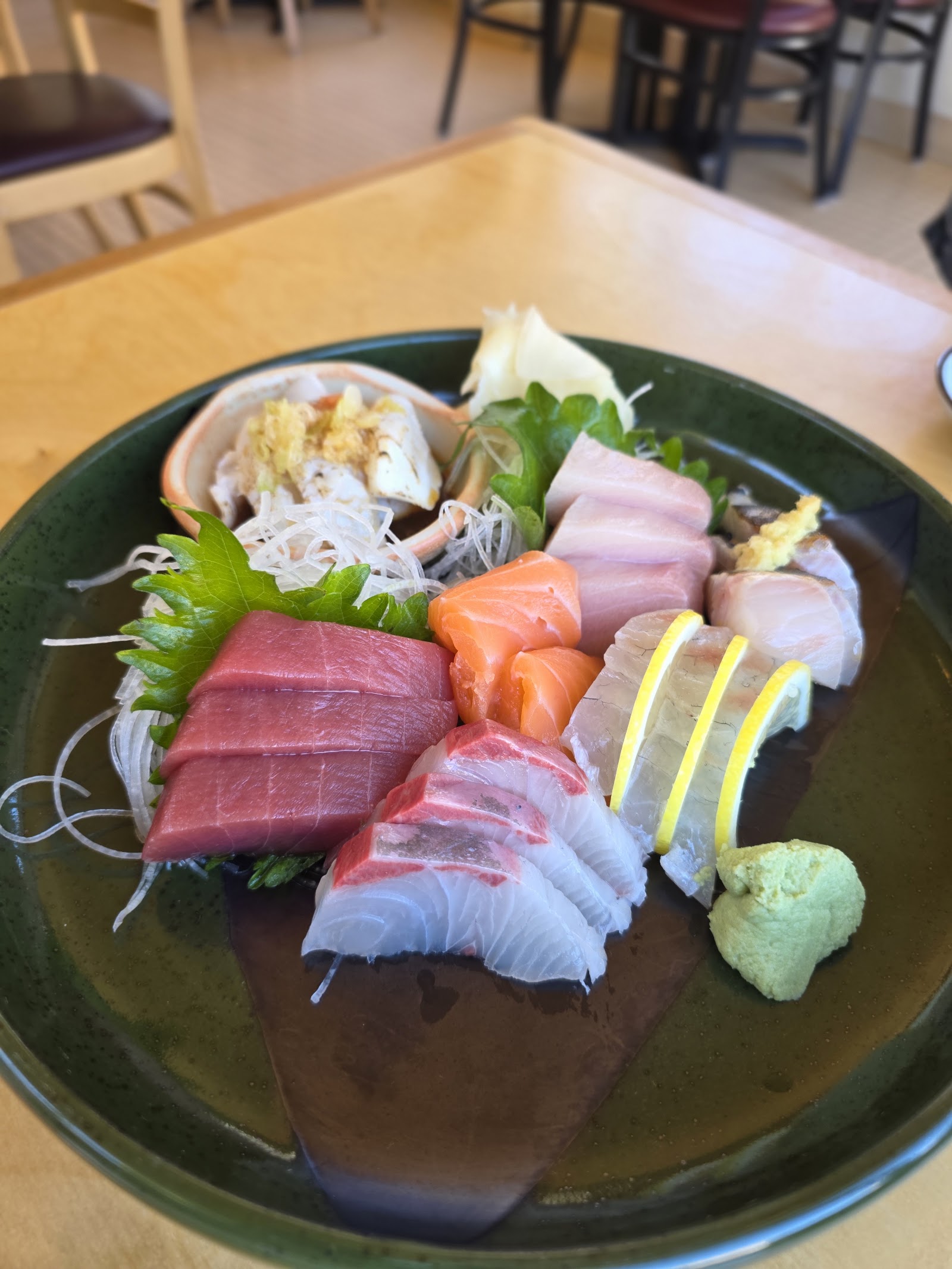 Assorted sashimi platter with tuna, salmon, pale fish, lemon, shiso, and wasabi