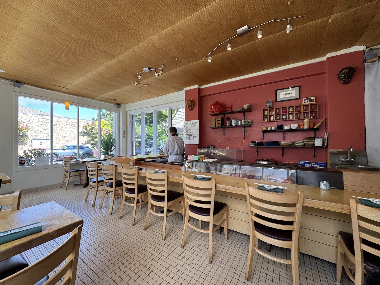 Sushi bar with chef, display case, and Japanese tableware